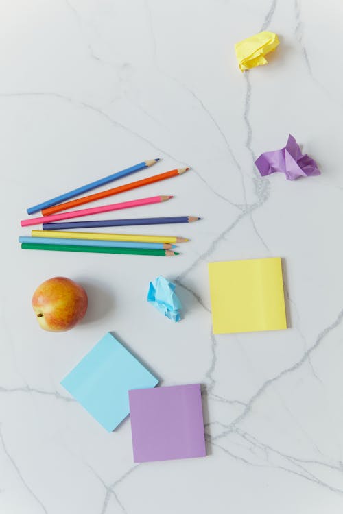 Fresh Fruit Apple and Colorful Stationeries on White Surface