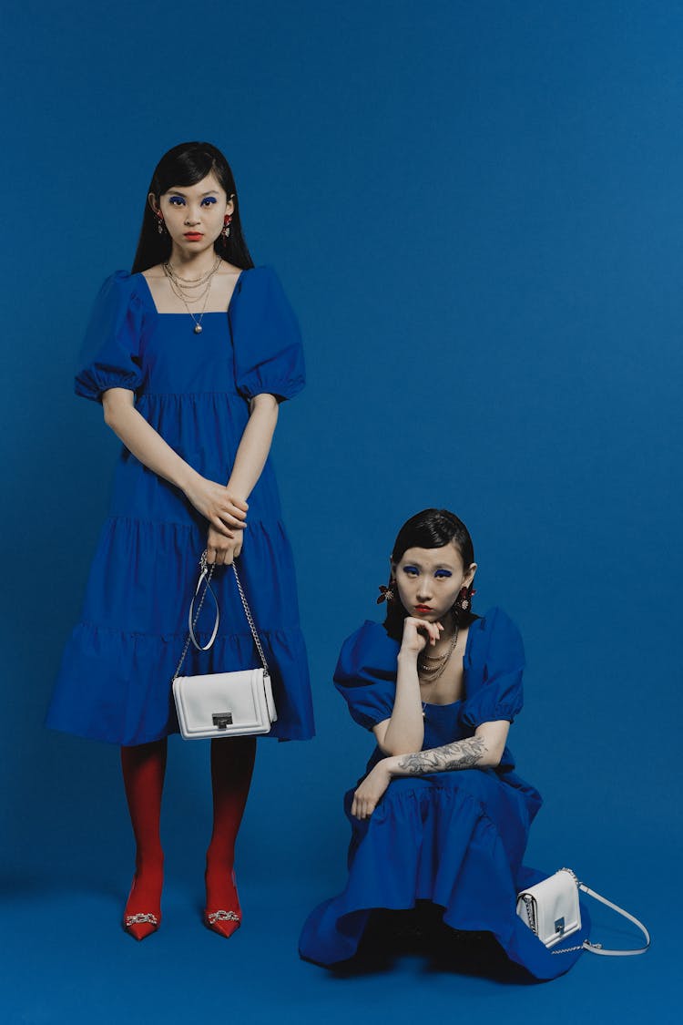 Women Wearing Blue Dress Holding Bags While Posing At The Camera