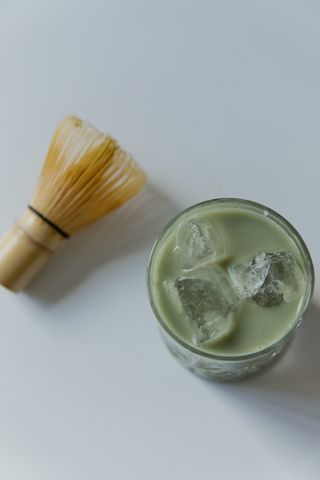 Iced matcha latte with a bamboo whisk on a white table — photo by Darina Belonogova on Pexels