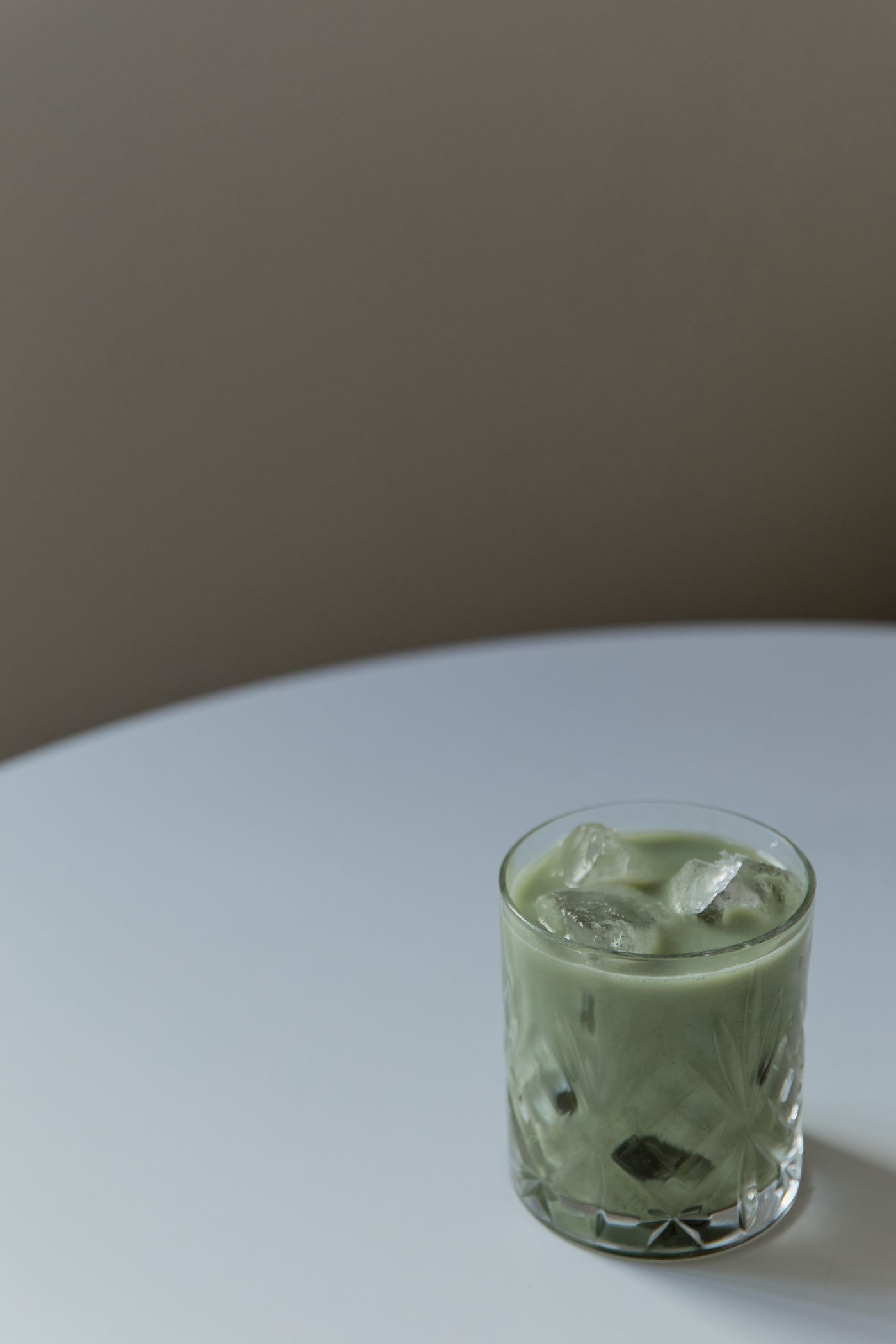 Glass of iced matcha latte on a round white table