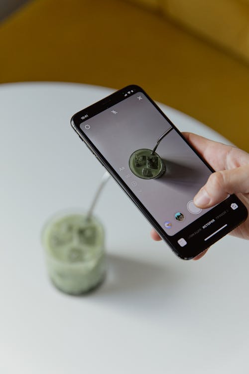 A Person Taking Pictures of a Glass of Matcha Latte