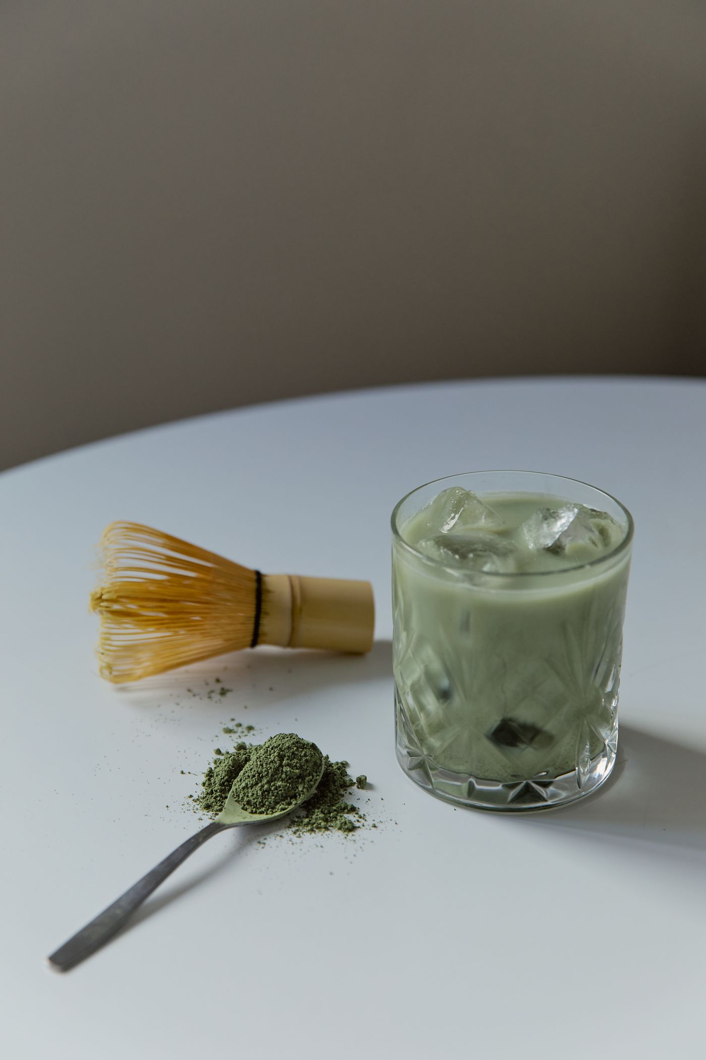 Iced matcha with a bamboo whisk and green tea powder.