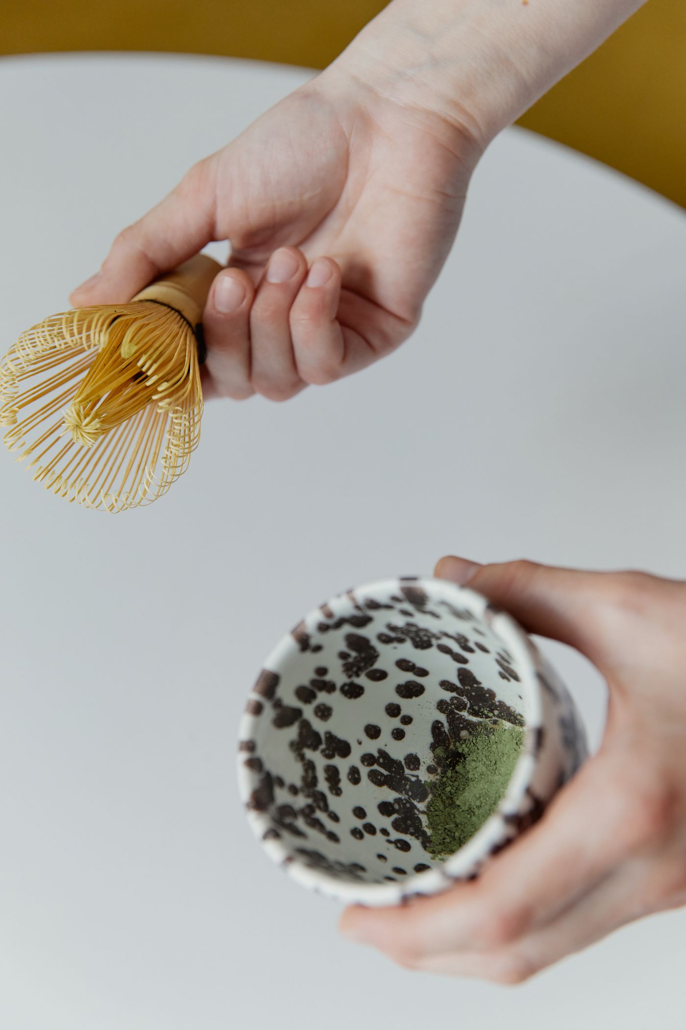 Hands whisking matcha in a ceramic bowl