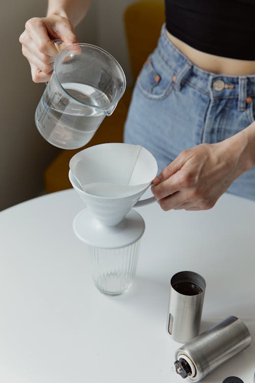 A Person Pouring Water on White Ceramic Cup with Filter
