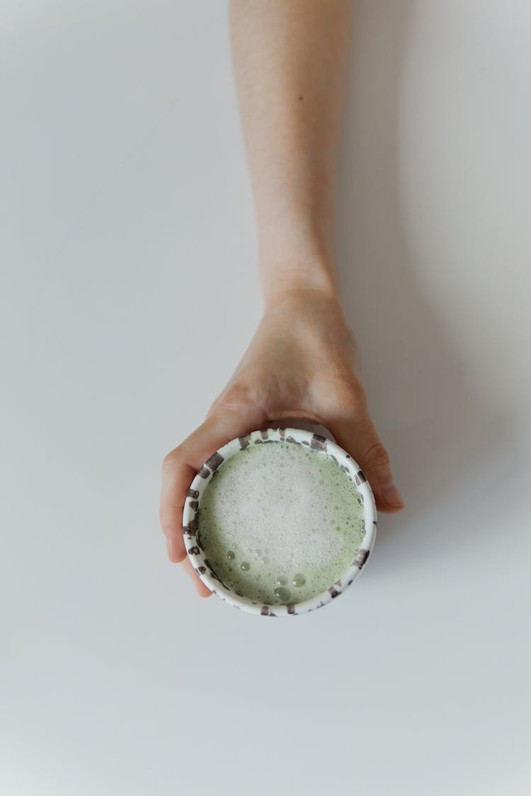 A Person Holding A Cup Of Bubbly Green Tea