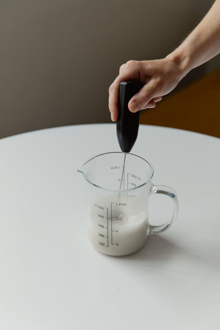 Hand Holding Mixer In Pitcher With Milk