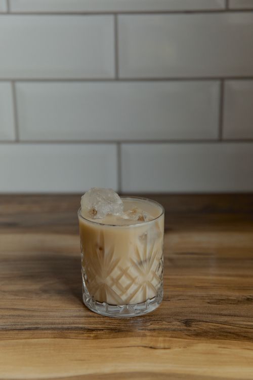 Free Enjoy a refreshing iced coffee served in an elegant crystal glass with ice cubes on a wooden table indoors. Stock Photo
