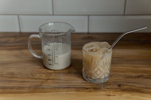 Measuring Cup Beside the Glass of Iced Coffee on a Wooden Surface