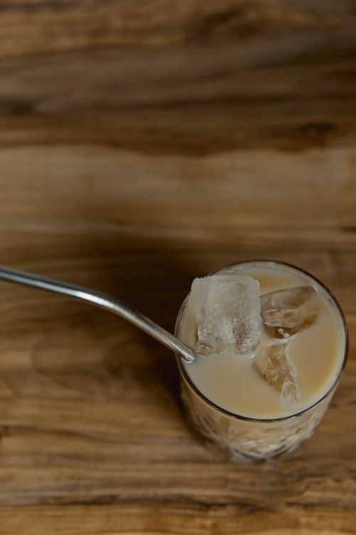 Free A top-down view of an iced coffee with a metal straw on wooden table. Stock Photo