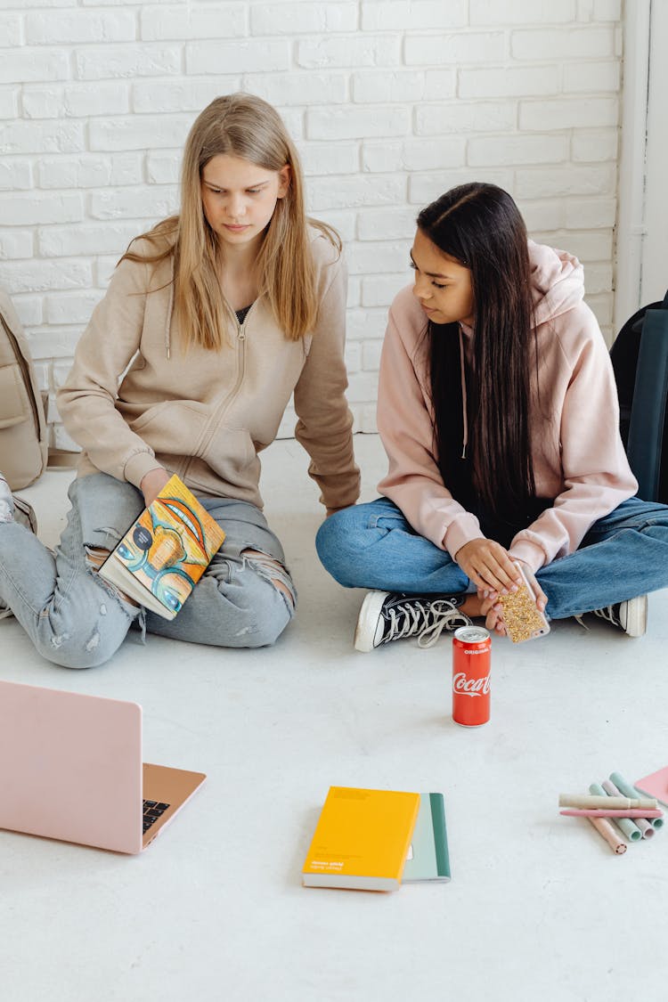 Women Wearing Jacket Sitting On The Floor While Talking To Each Other