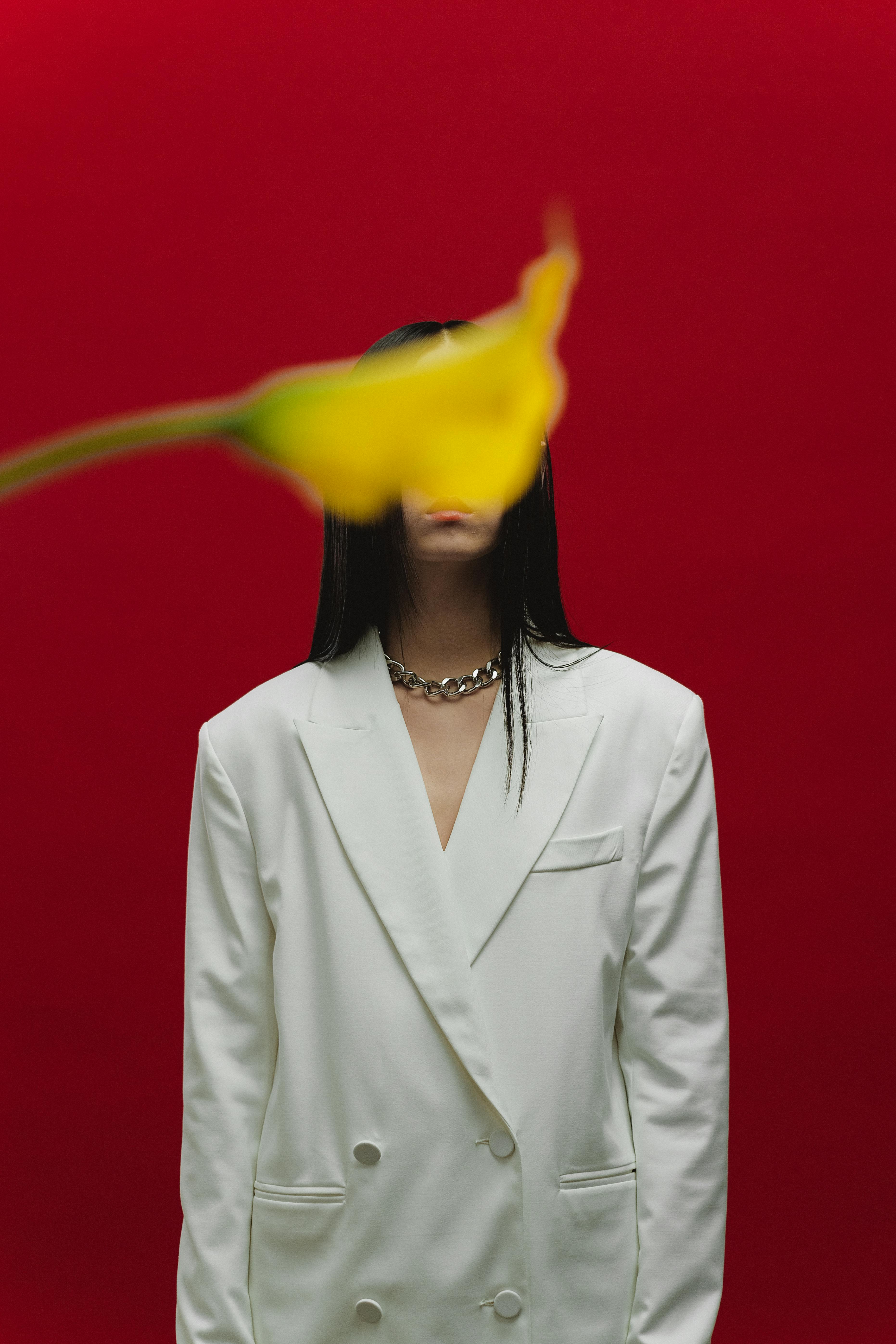 [ColoSach]-creative-portrait-with-a-white-blazer,-flower-in-focus-against-a-bright-red-backdrop