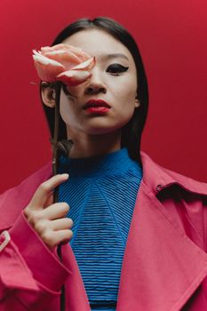 Captivating portrait of a woman with a rose, featuring bold colors and striking makeup.
