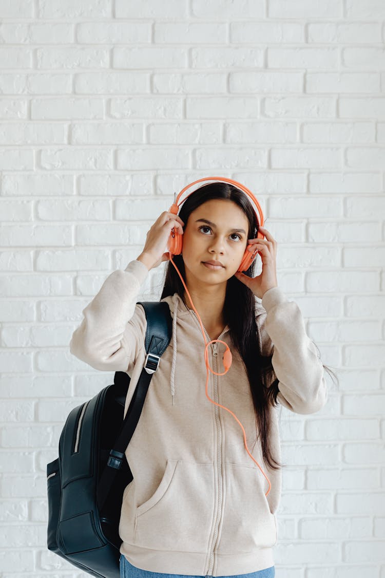 A Young Girl Carrying Backpack While Wearing  Headphones