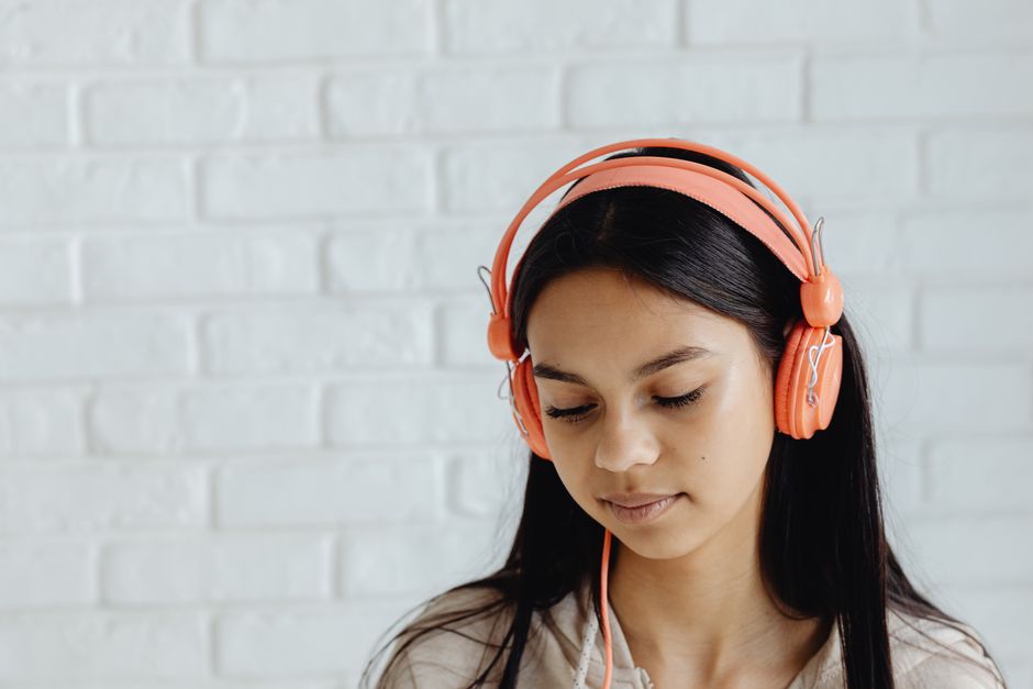 A woman listening to headphones in a soft natural light, the calm slow attention that botanical listening rewards.