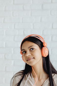 Young girl listening to music with orange headphones, enjoying tunes.