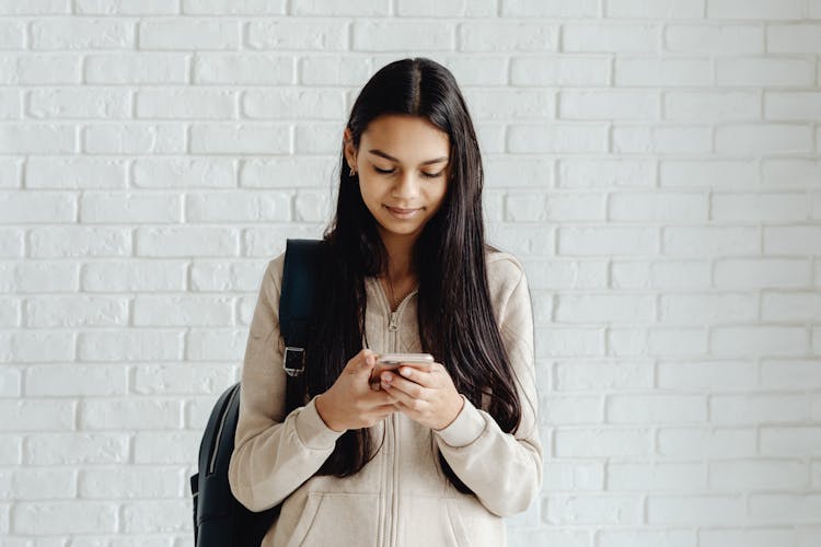 Young Woman With Long Hair Busy Using Cellphone