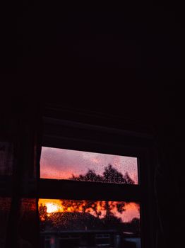 A dramatic sunset seen through a raindrop-covered window, creating a tranquil and reflective mood.