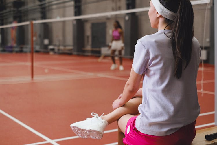 A Woman Sitting And Watching A Badminton Game