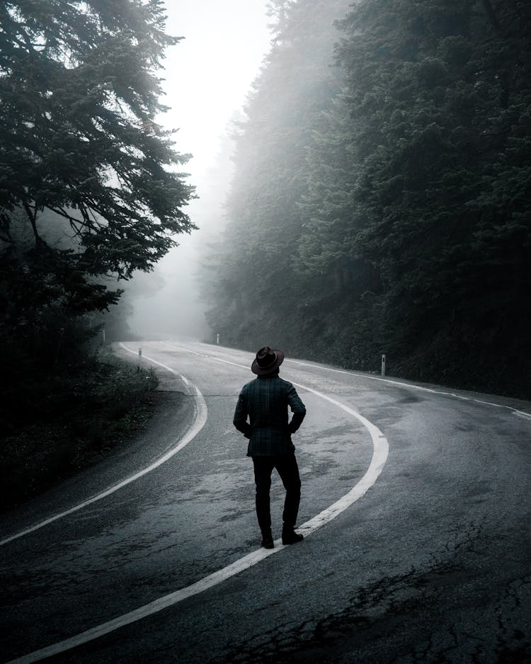 Man Walking Along Road In Forest