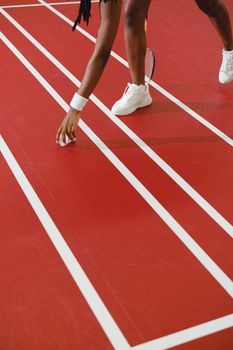 Close-up of a woman's hand picking up a shuttlecock on a red indoor badminton court.