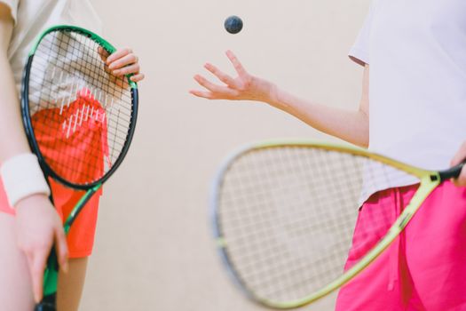Two tennis players with rackets and a tennis ball, captured in an indoor sports setting.