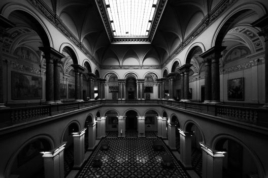 Black and white photo of ornate Renaissance-style hall with arches and columns.