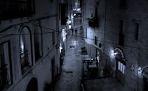 夜晚，路灯照亮了城市中黑暗狭窄的小巷，两个人行走其中