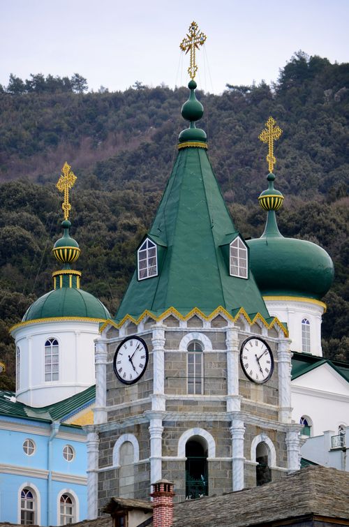 Free Exterior view of an Orthodox church with green domes and golden crosses against a wooded hillside. Stock Photo
