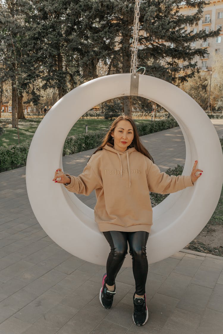 Cool Ethnic Woman On Ring Swing In City Park