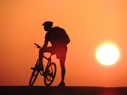 A Silhouette of a Man with His Bicycle