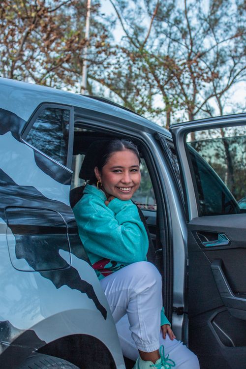 Free A cheerful young woman sits comfortably in a parked car, smiling at the camera on a sunny day. Stock Photo