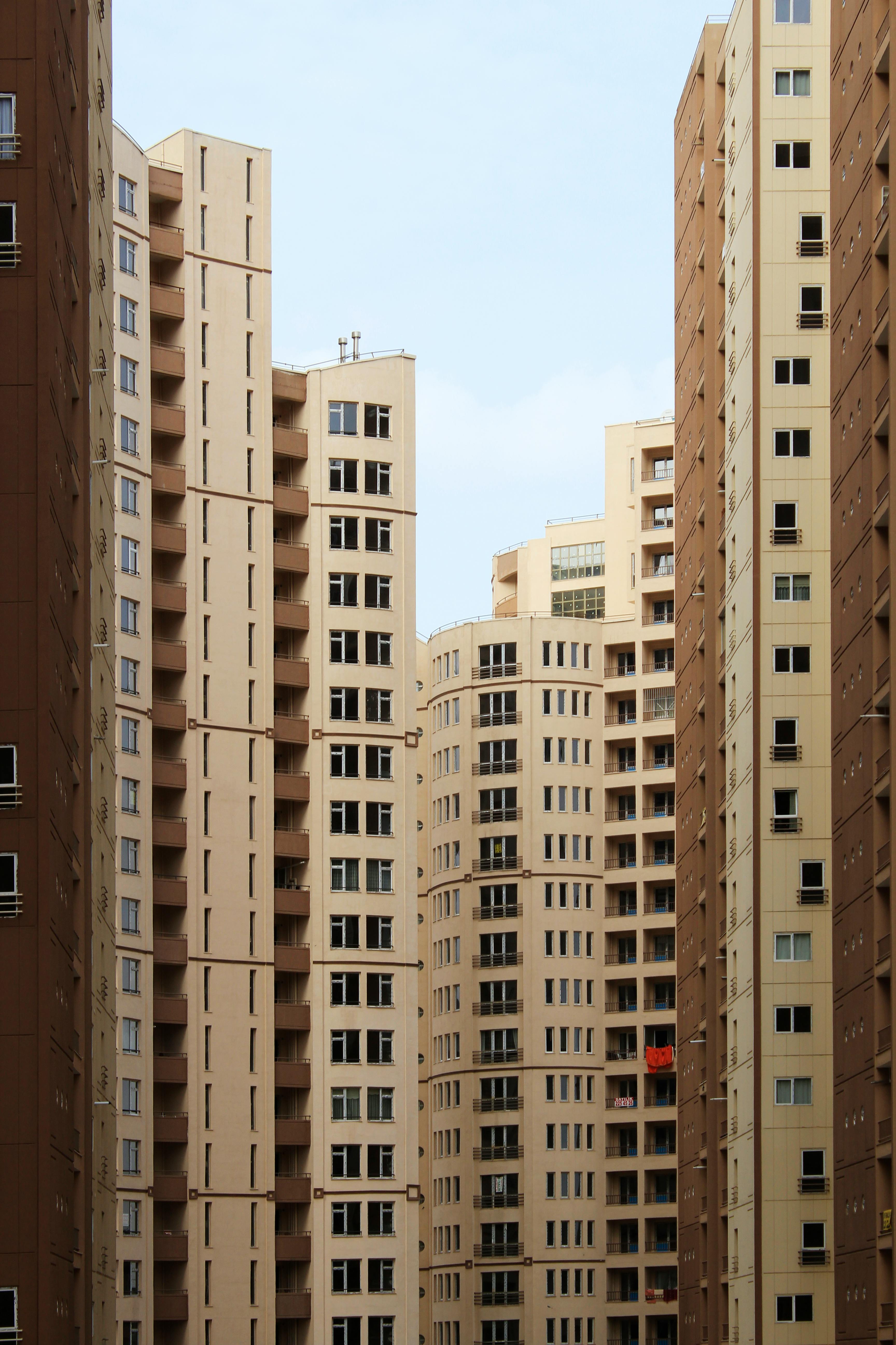 Vertical shot of modern high-rise buildings against a clear sky in an urban setting.