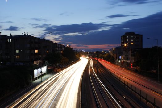 Long exposure photo capturing light trails on a bustling highway at twilight.