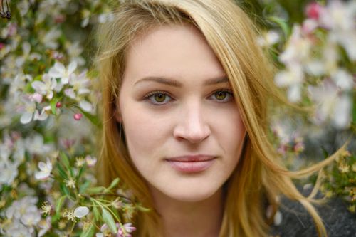 Free Close-up portrait of a woman with floral background capturing natural beauty. Stock Photo