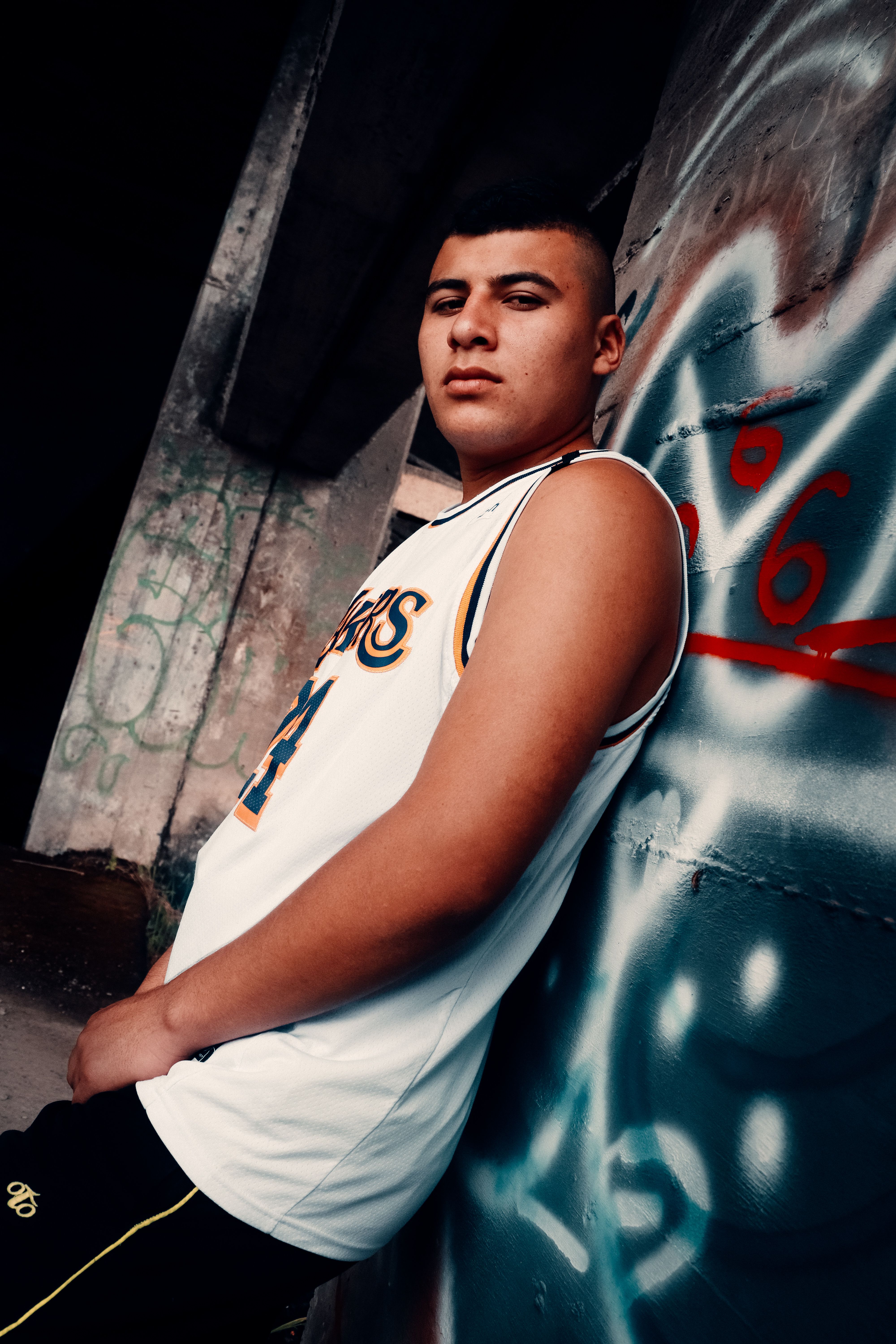 Young man leaning against a graffiti wall in Caldas, Colombia. Urban street style.