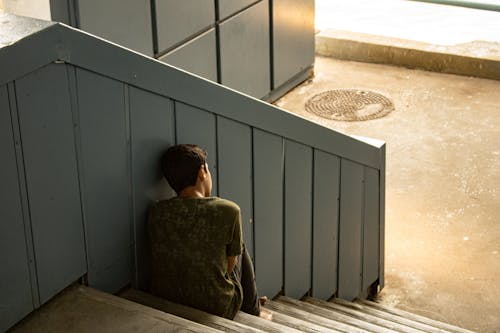 Free Back View Shot of a Young Man Sitting on the Stairs  Stock Photo