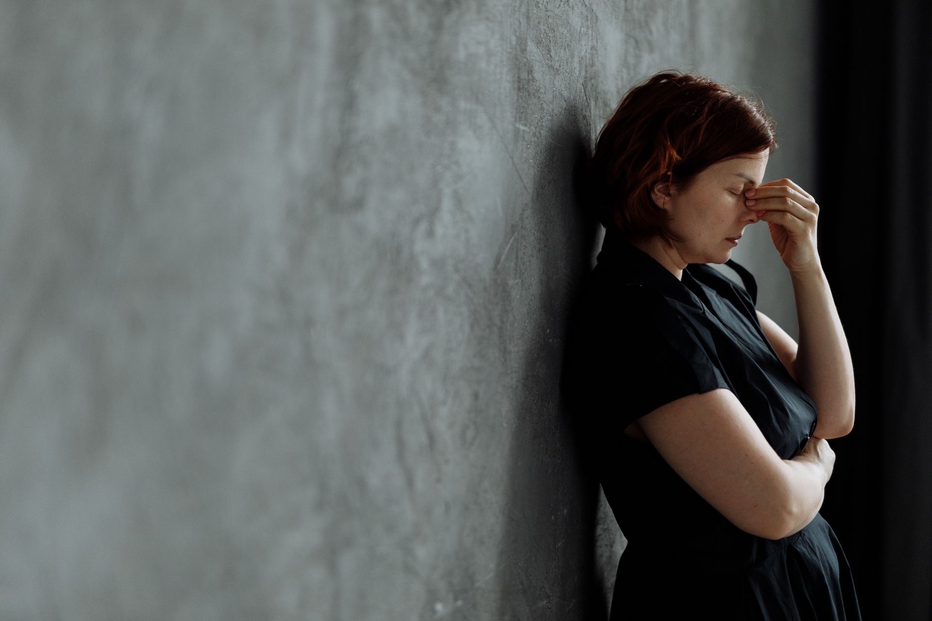 A Stressed Woman Leaning on a Concrete Wall