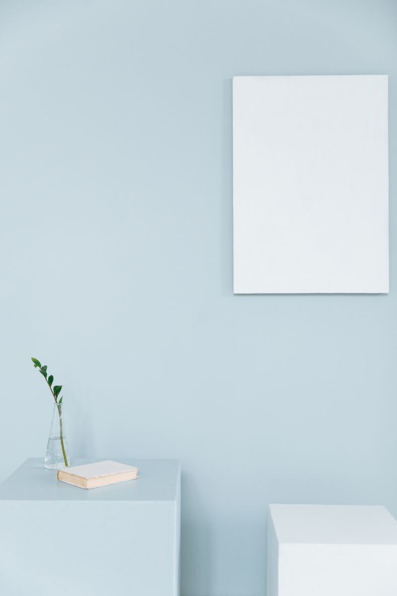 Minimalist setup with a vase, book, and blank canvas on blue cubes.