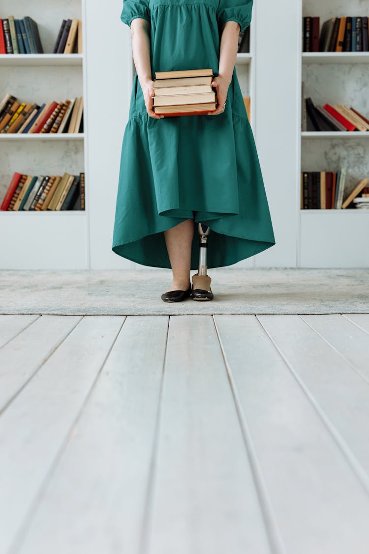 A Woman Holding A Stack Of Books