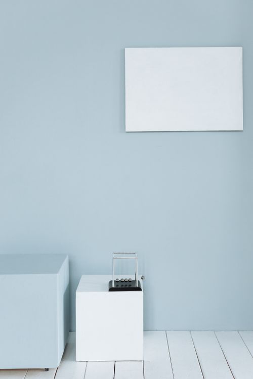 Free Minimalist room featuring a light blue wall with a white frame and cubes. Stock Photo