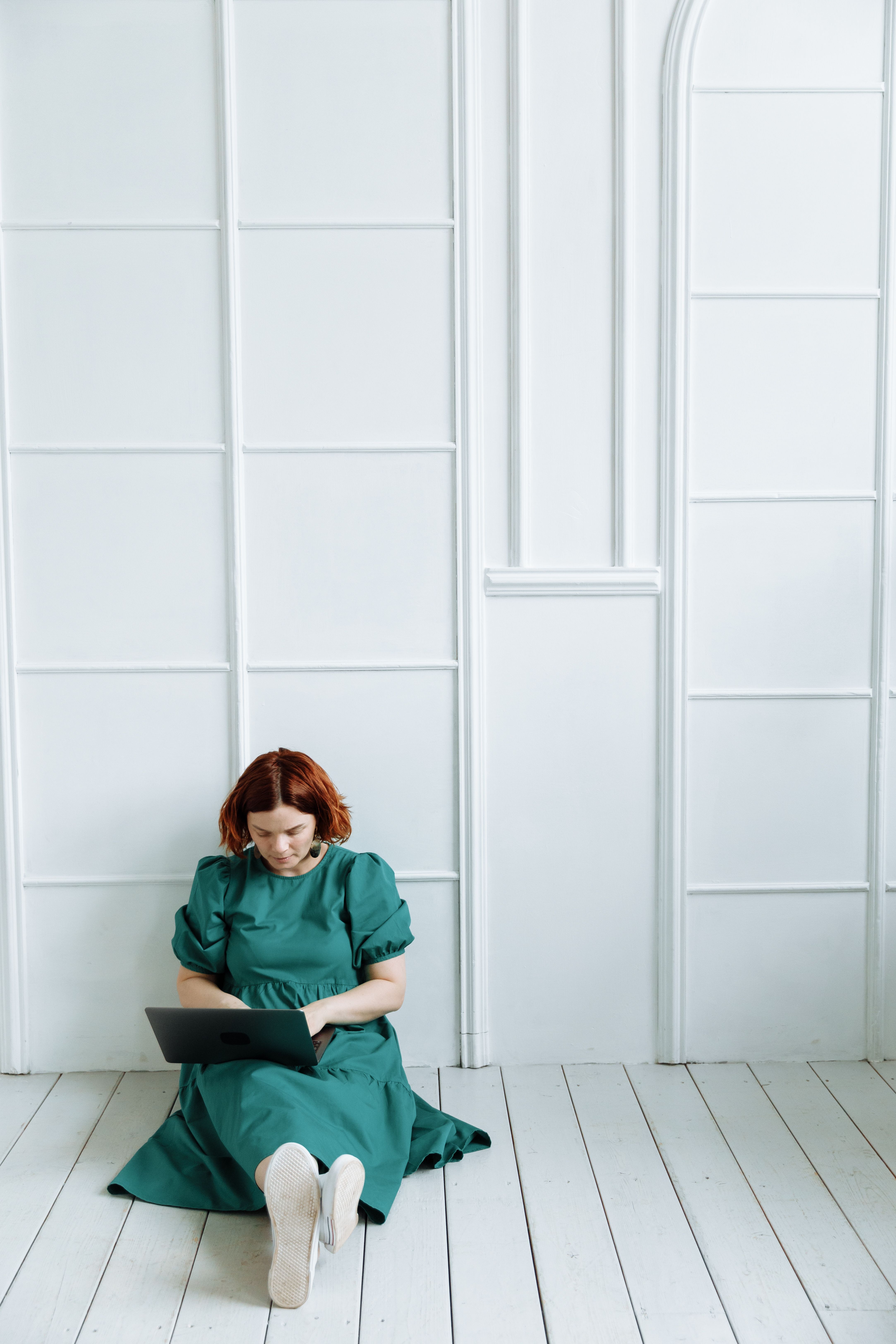 A Woman in a Green Dress Working while Sitting on the Floor · Free ...