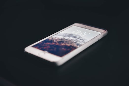 Close-up of a modern smartphone displaying mountain landscape, time shown as 23:32.