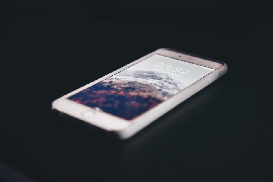 Close-up of a modern smartphone displaying mountain landscape, time shown as 23:32.