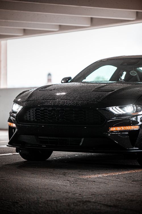 Free Shiny black sports car parked in an indoor parking garage, covered with raindrops. Stock Photo