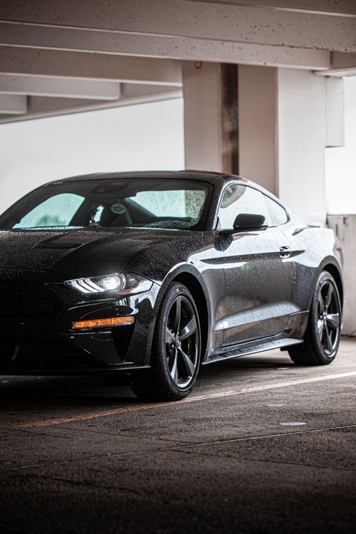 Free Luxury black car in a parking garage with water droplets after rain, showcasing elegance and style. Stock Photo
