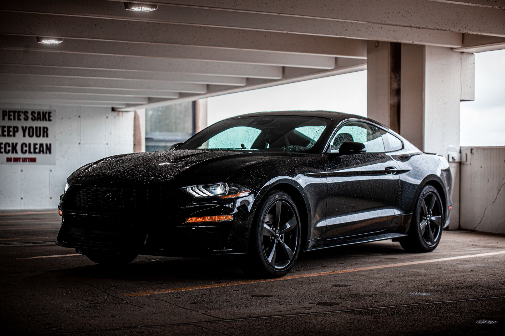 A black Ford Mustang parked indoors in a dimly lit garage with sleek, modern design.