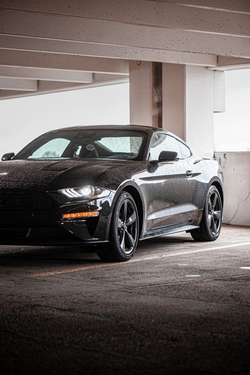 Free A shiny black sports car parked under a concrete structure, showcasing elegance and power. Stock Photo