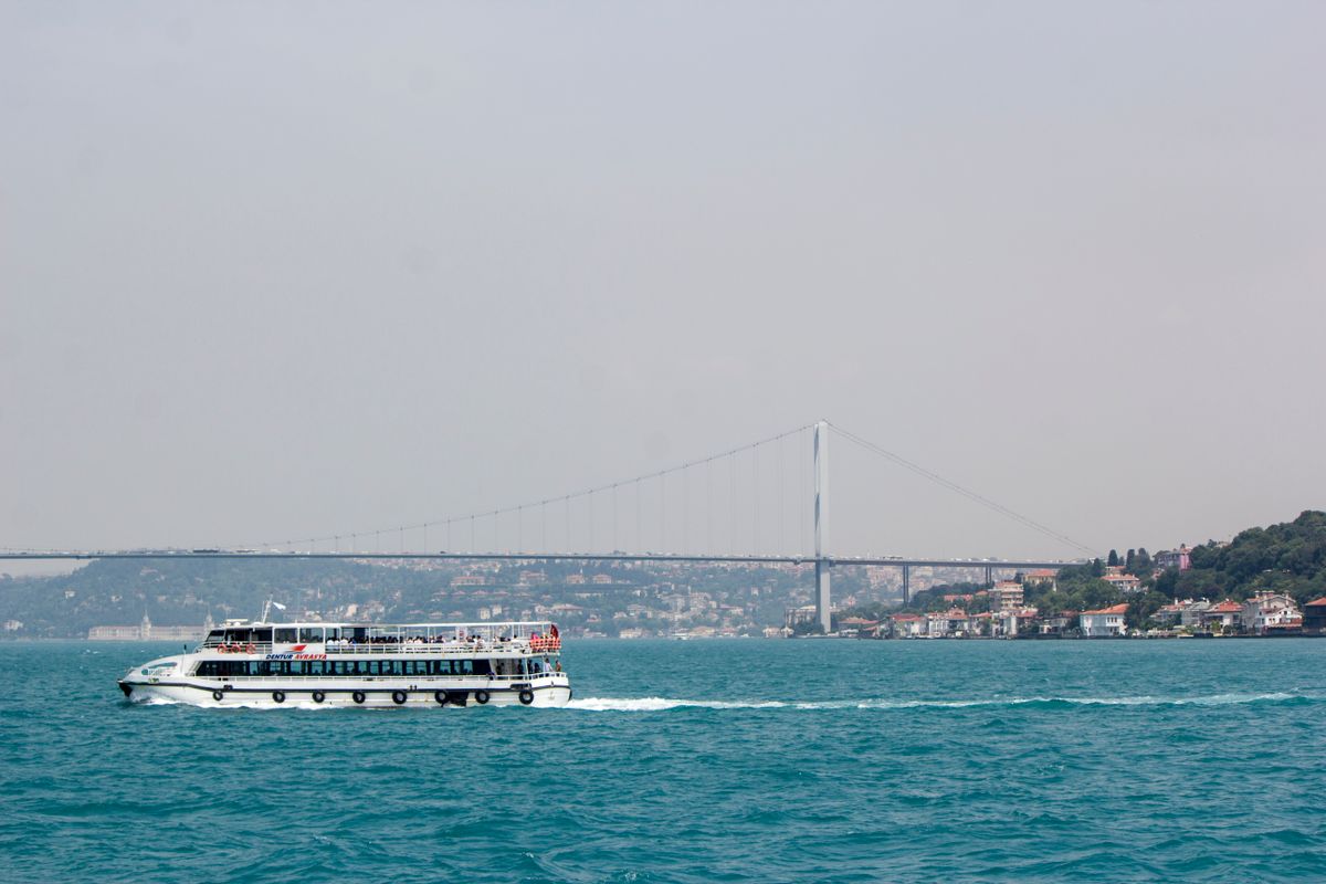 A tour ferry on the Bosphorus with the Bosphorus Bridge and waterfront mansions behind