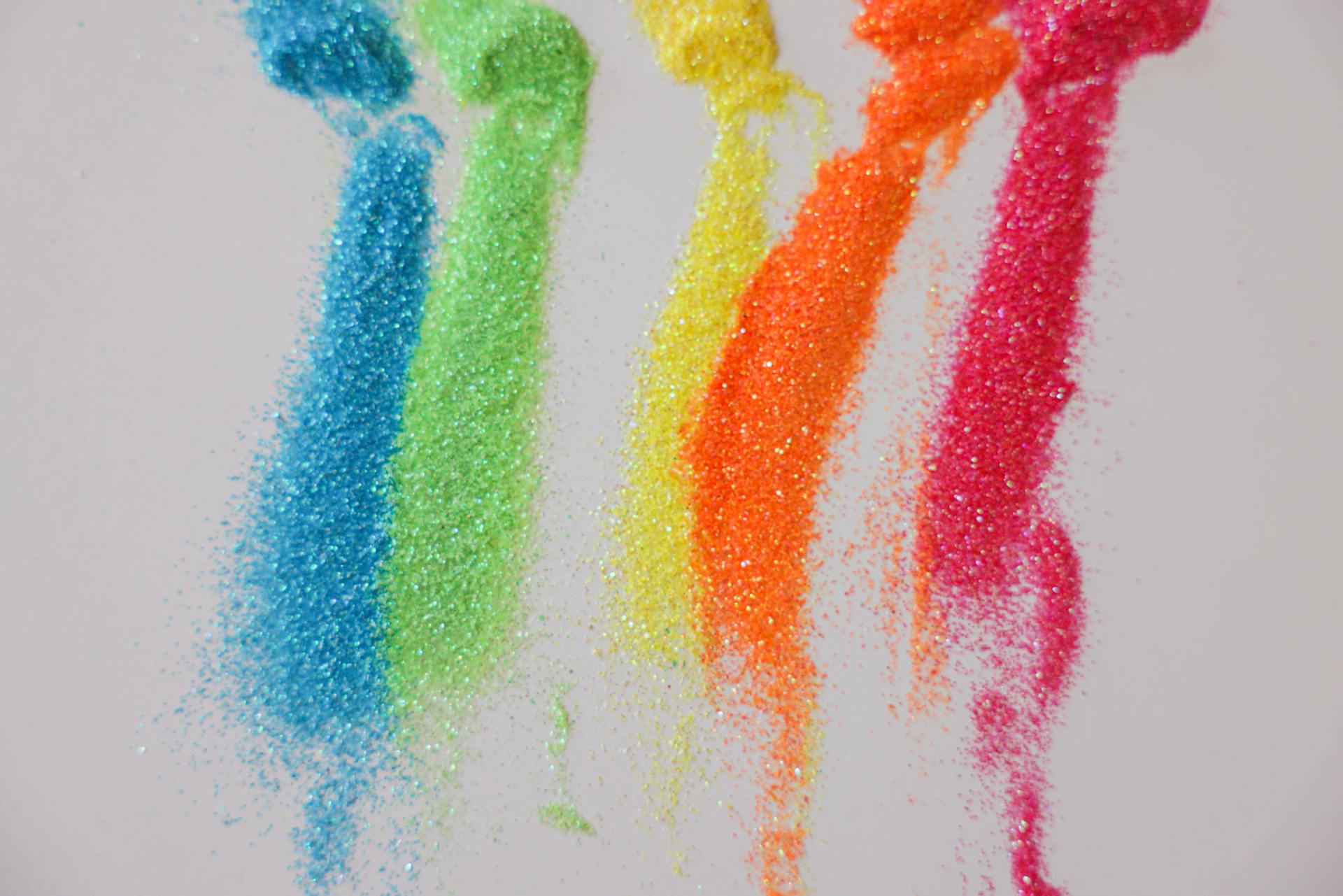 Close-up of colorful glitters on a white background showcasing bright rainbow colors.