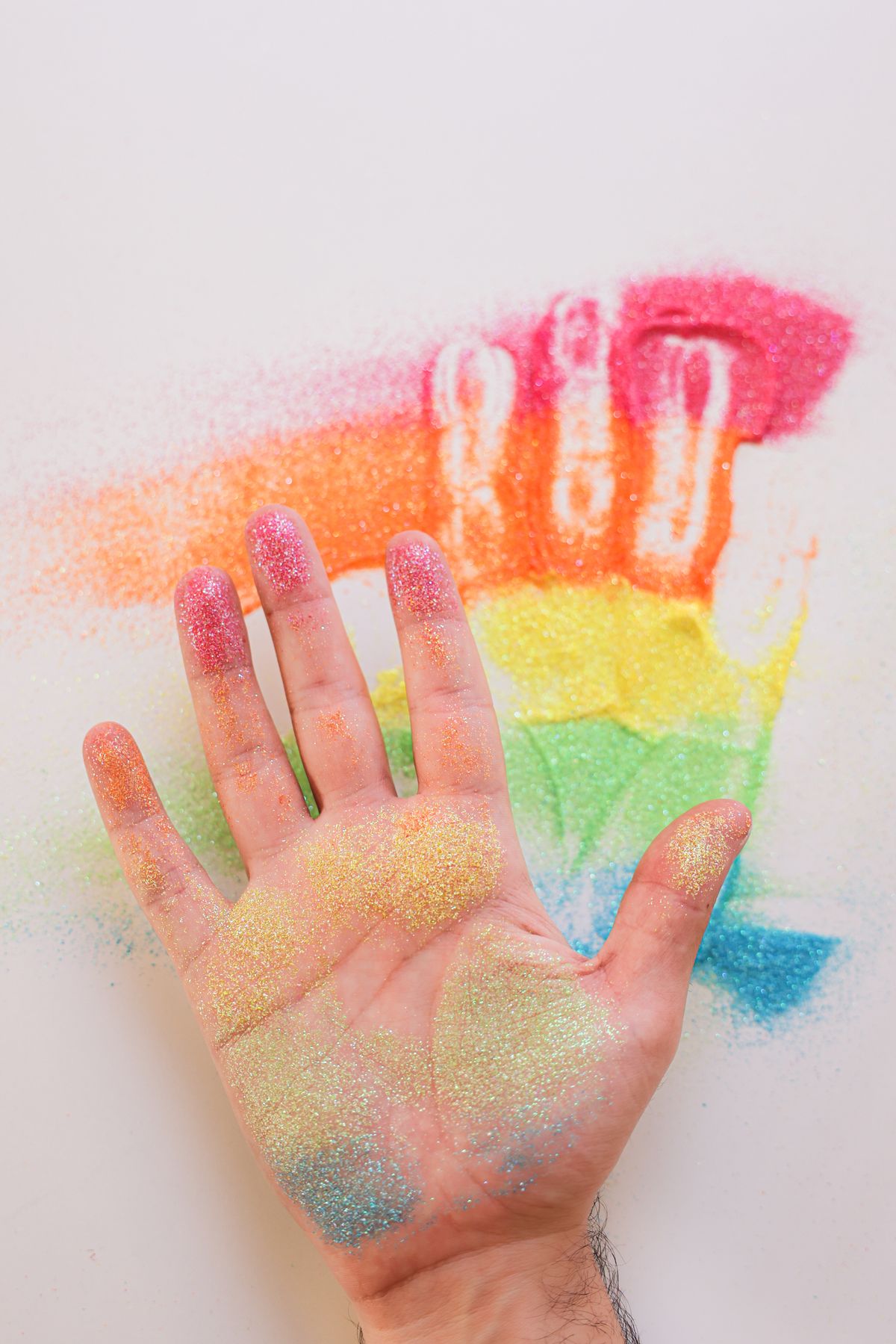 A palm covered in vibrant, rainbow-colored craft sand